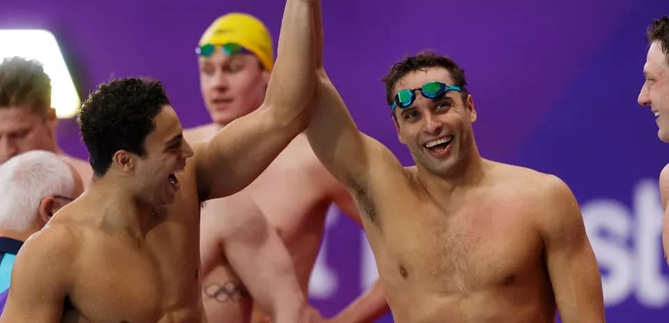 Swimmers celebrating with raised arms after competition