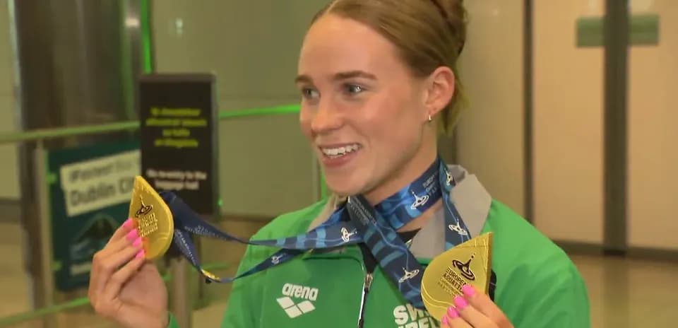 Athlete displaying gold medals at arrival terminal