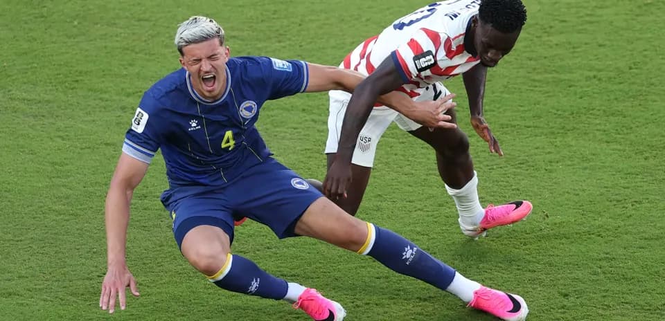 Bosnia player falls while competing for the ball