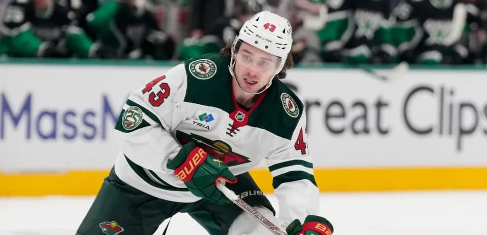 Hockey player skating with puck on ice rink
