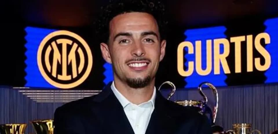 Futbolchi Inter emblemi oldida tabassum qilmoqda