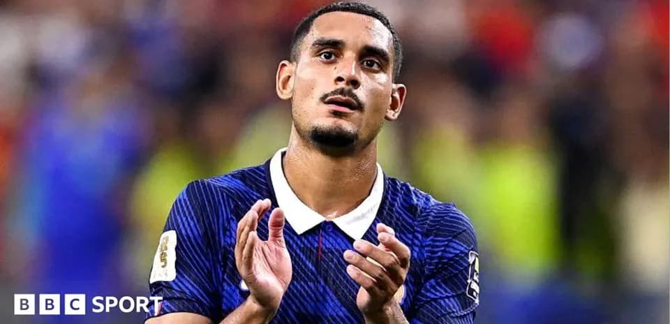 Futbolchi maydonda qo'llarini ko'tarib turgan