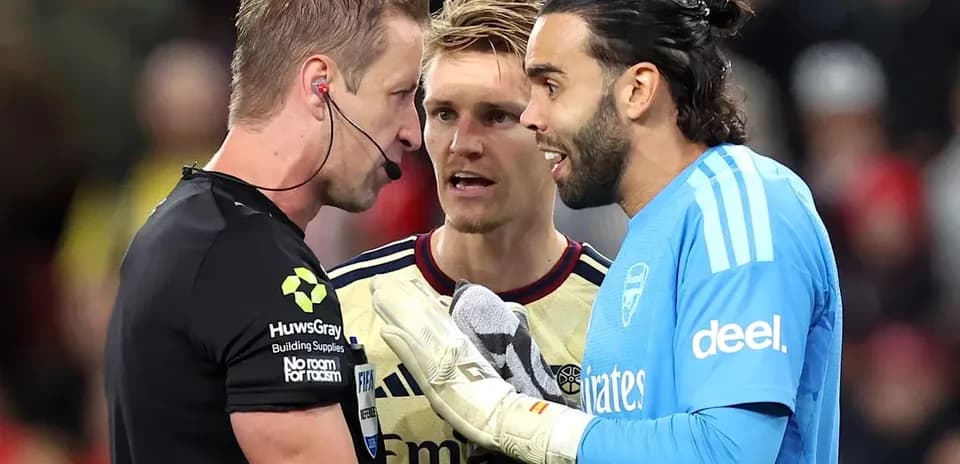 Goalkeeper and players discussing with referee on field