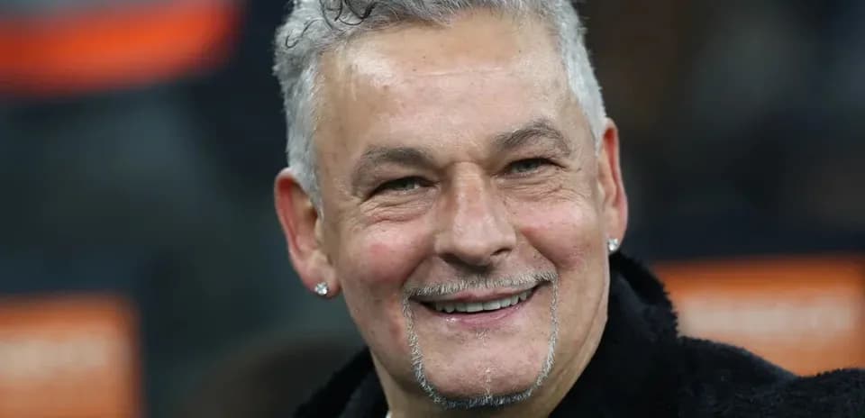 Smiling man with curly hair and earrings