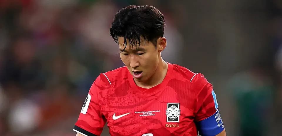 Koreyalik futbolchi o'yin davomida boshini egib turibdi