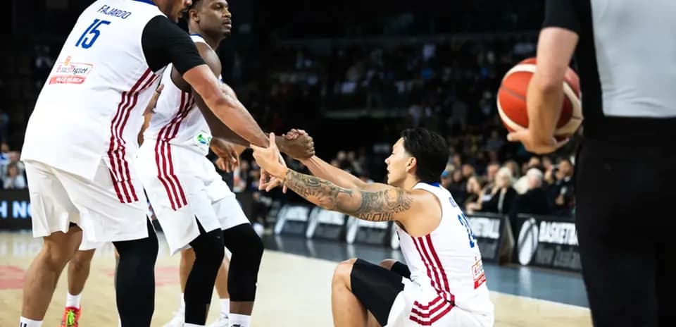Two players assisting teammate sitting on court
