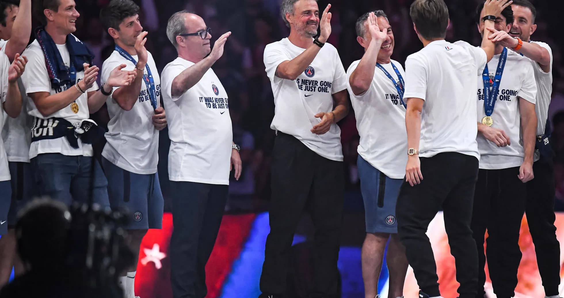 Coaches and staff celebrating on stage after victory