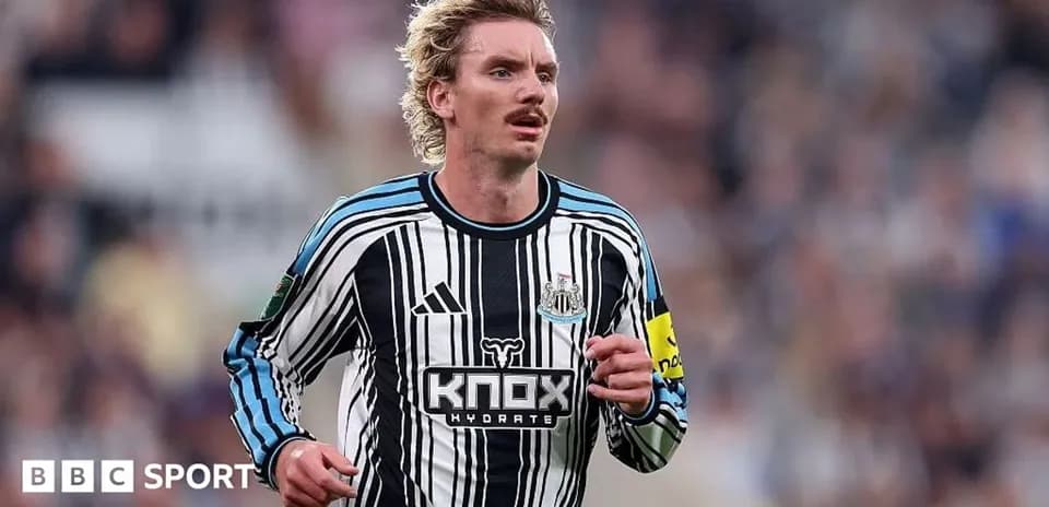 Futbolchi Newcastle formasida maydon bo'ylab yugurmoqda