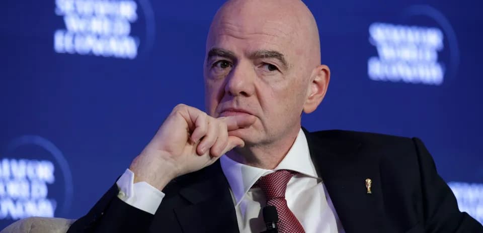 Man speaking at a conference with a thoughtful expression