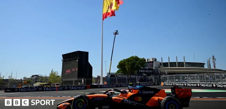 Formula 1 car passing under Spanish flag at circuit