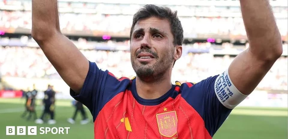 Futbolchi Ispaniya formasida maydonda qo'lini ko'tarayotgan