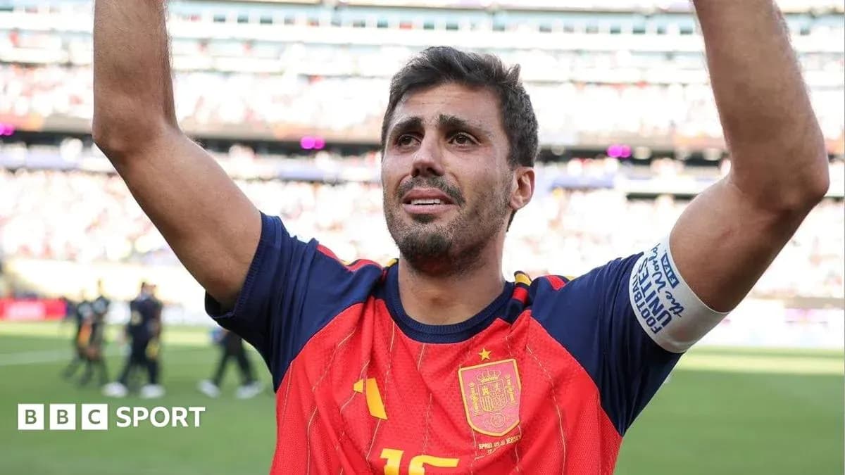Futbolchi Ispaniya formasida maydonda qo'lini ko'tarayotgan