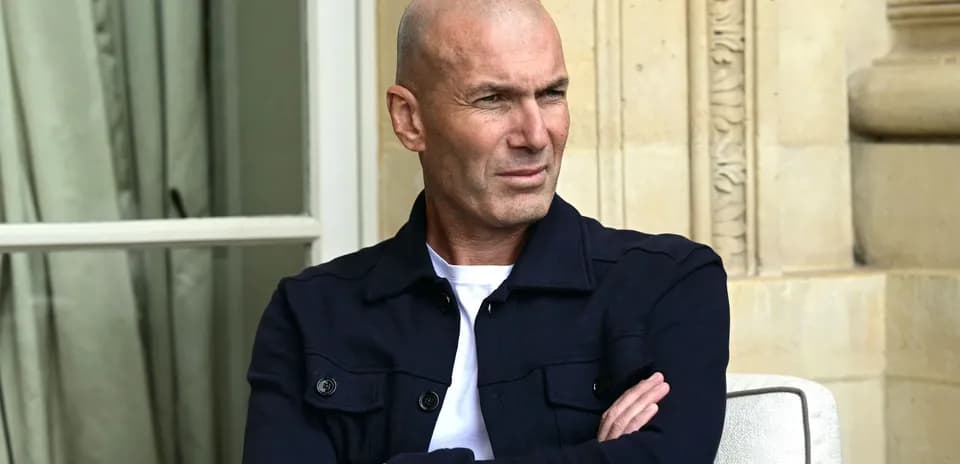 Bald man sitting with crossed arms outdoors