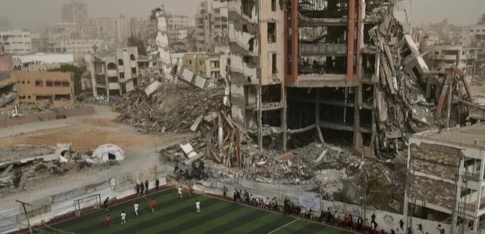 Football match in front of destroyed buildings
