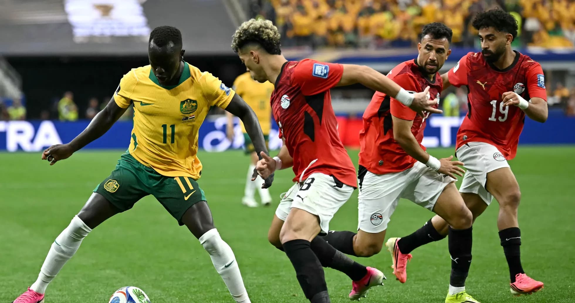 Australia player dribbling past Egyptian defenders during match