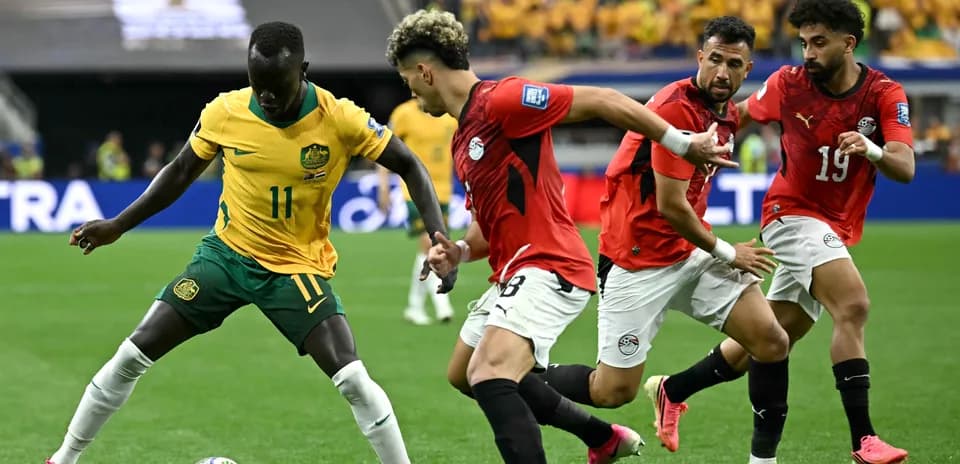 Australia player dribbling past Egyptian defenders during match