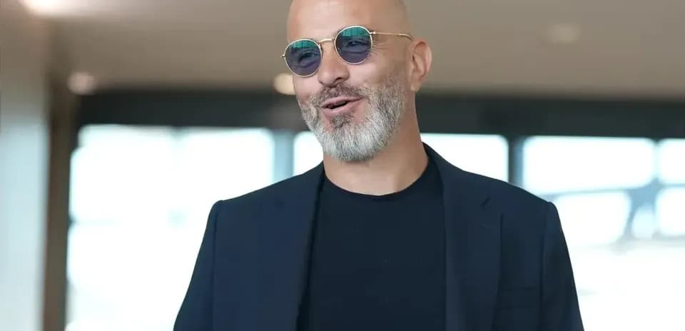 Man in sunglasses smiling in indoor setting