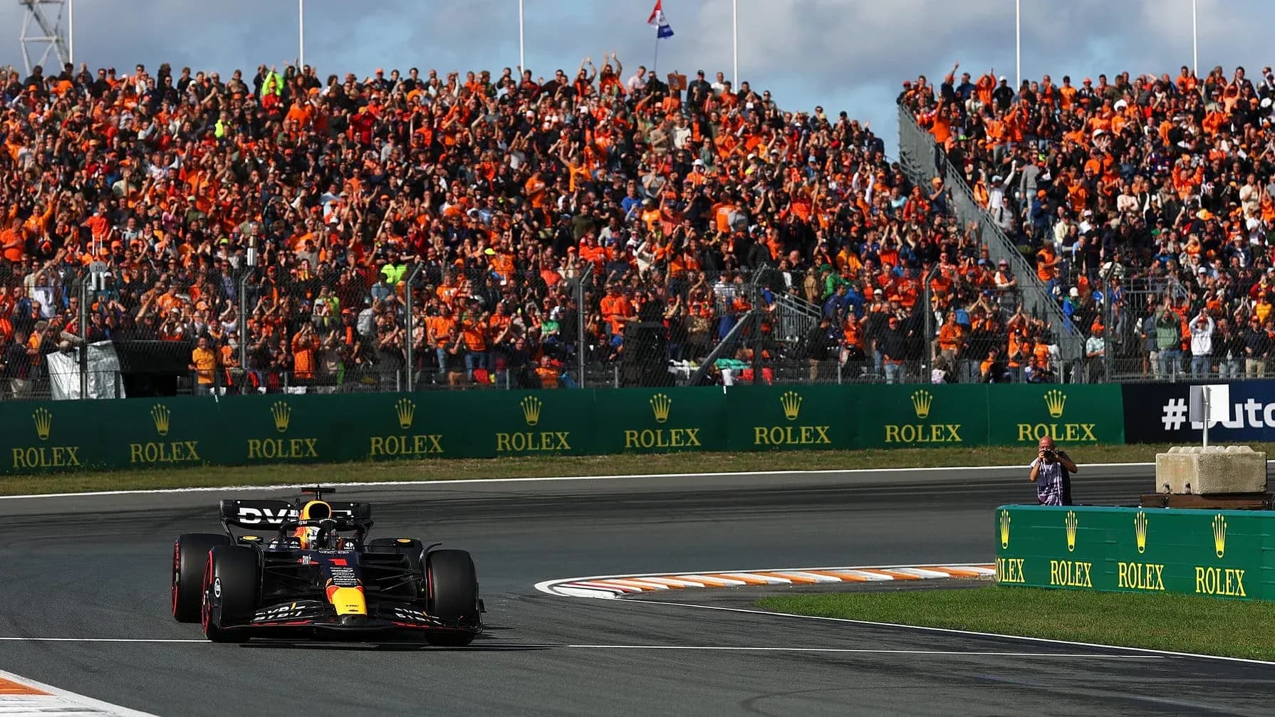 Formula 1 car racing past cheering crowd in orange