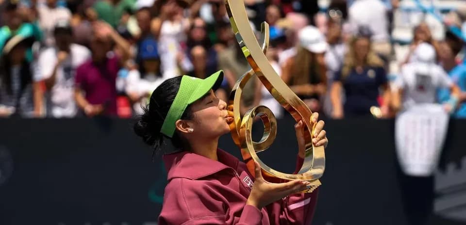 Tennis player kissing trophy after winning match