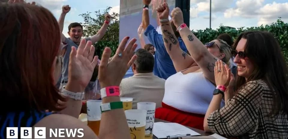 People celebrating at outdoor venue with raised hands