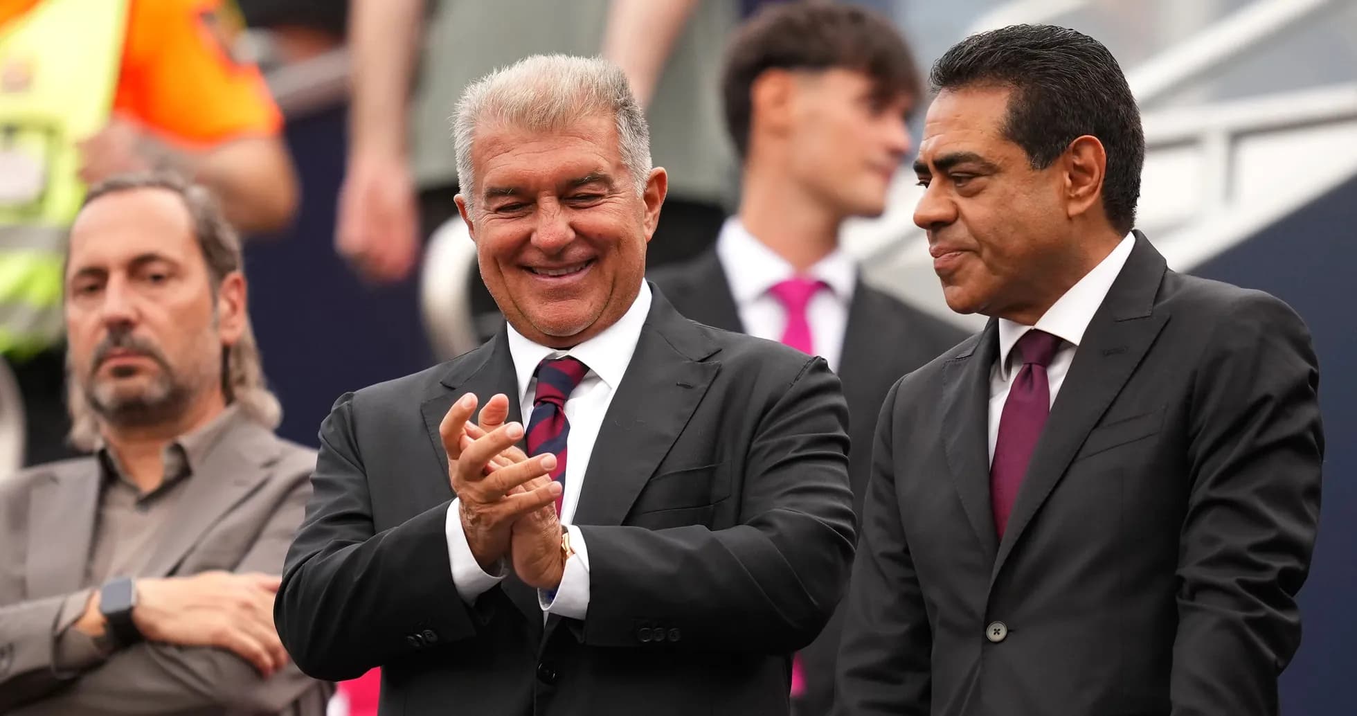 Three men in suits at a sports event