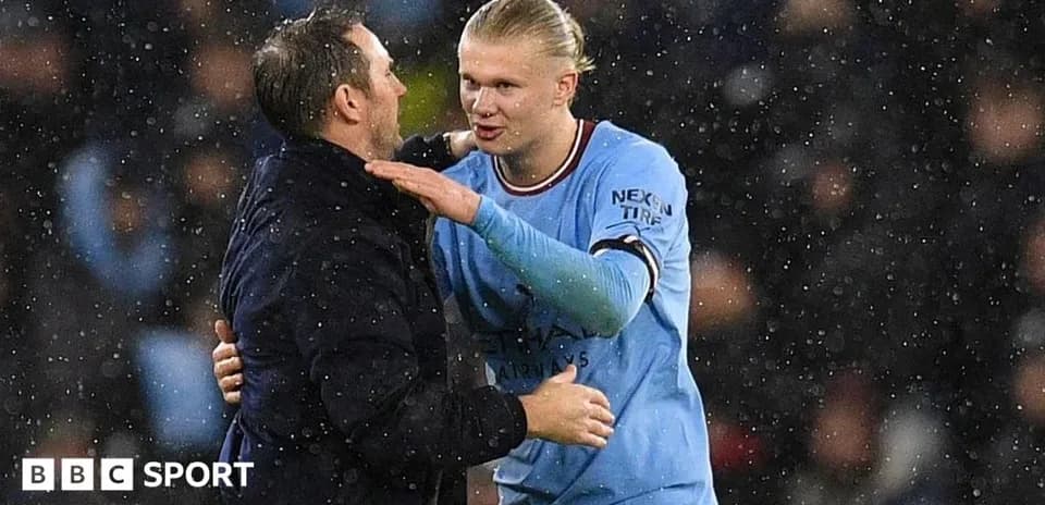 Erling Haaland embracing coach during rainy match
