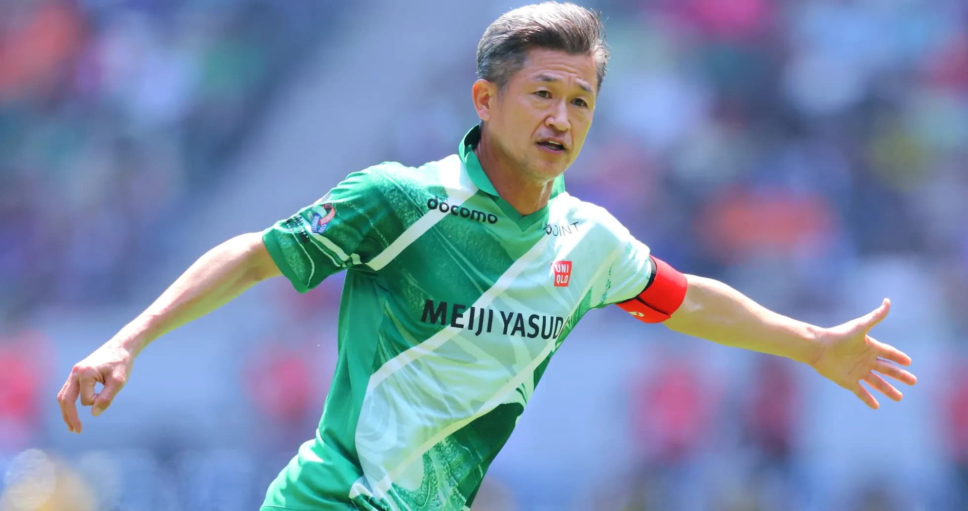 Futbolchi maydonda harakatda, yashil forma kiygan
