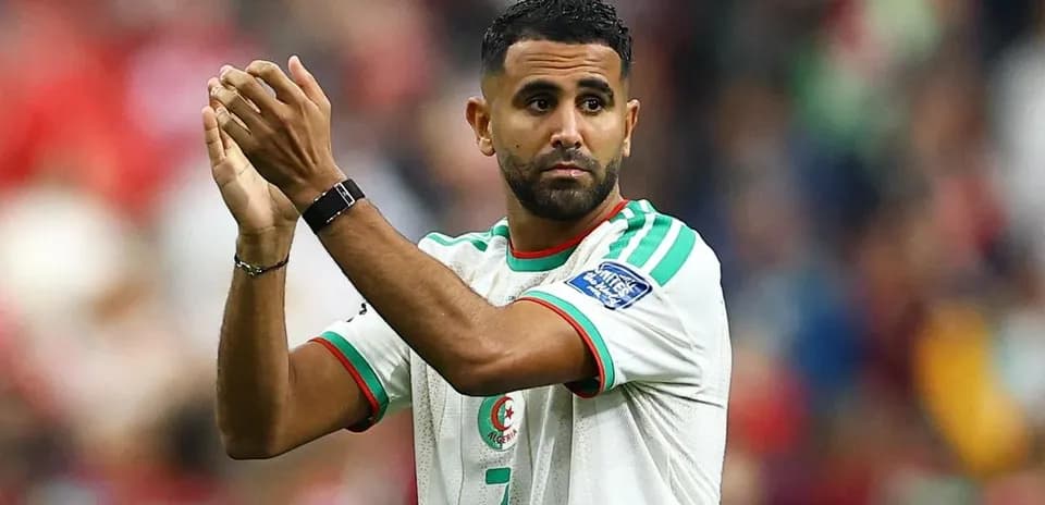 Futbolchi maydonda qo'lini ko'tarib turgan