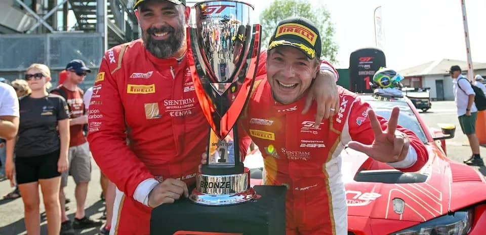 Two drivers celebrating with trophy after race