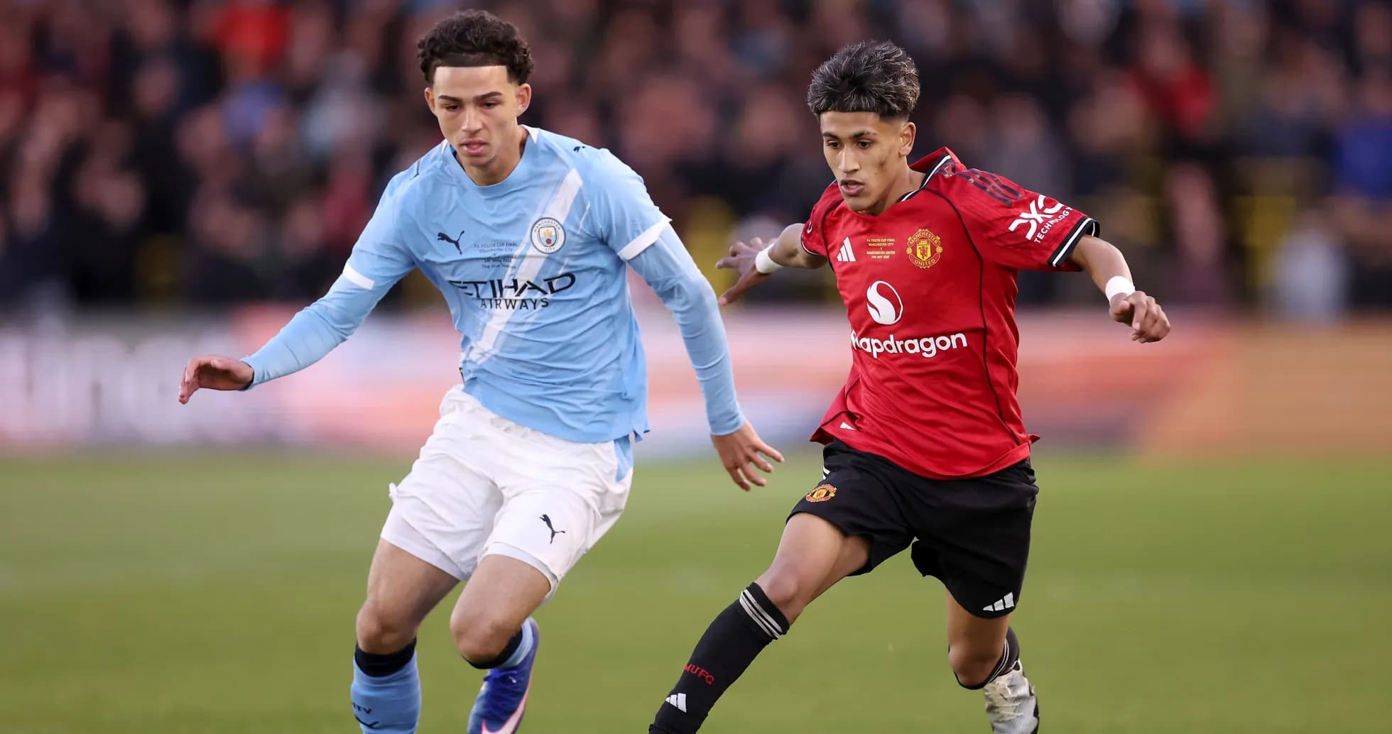 Manchester City and Manchester United players competing for the ball