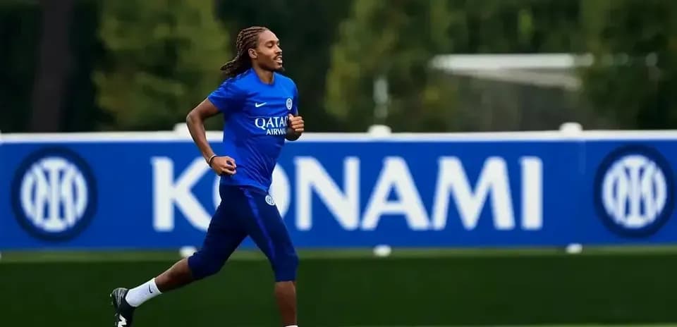 Futbolchi mashg'ulotda yugurmoqda, orqa fonda banner