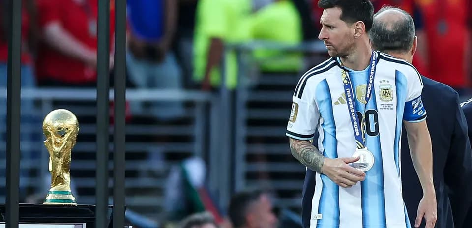 Lionel Messi walking past the World Cup trophy