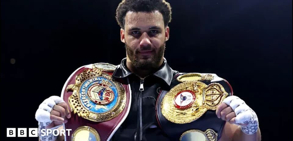 Boxer holding multiple championship belts in ring