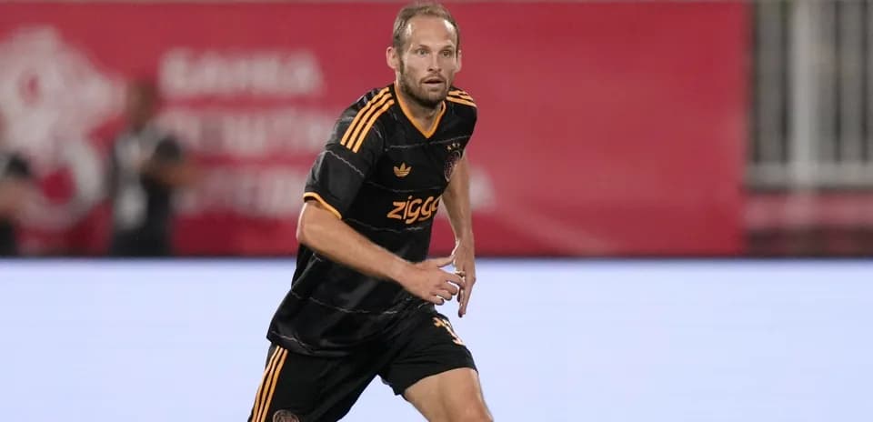 Futbolchi maydonda harakatda, qora forma kiygan