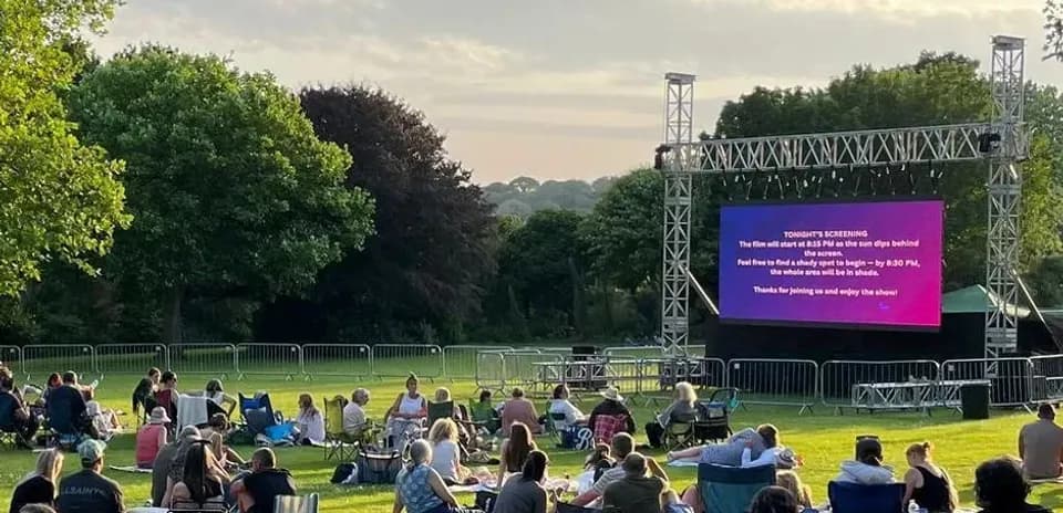People watching a movie outdoors on a large screen