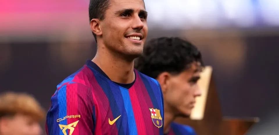 Futbolchi ochiq maydonda kubok bilan tabassum qilmoqda