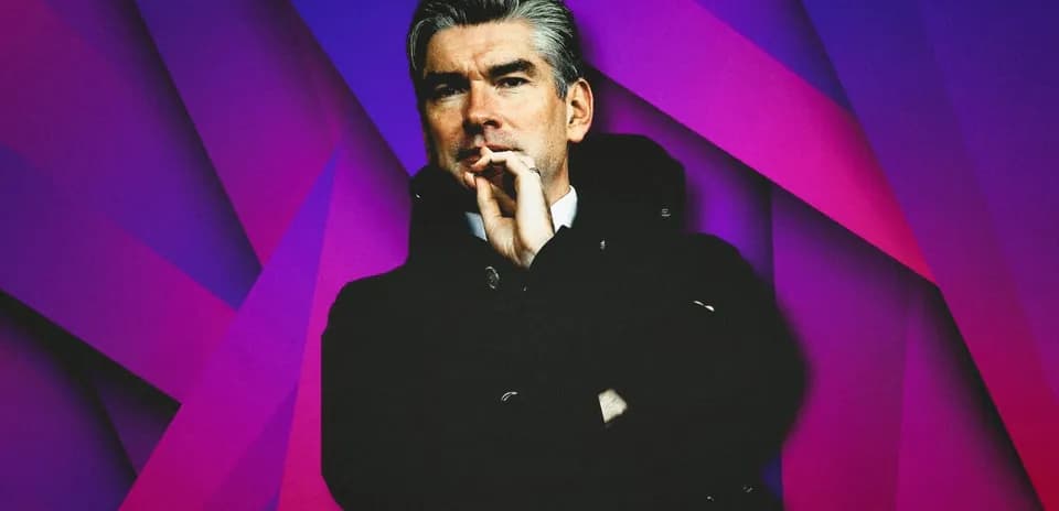 Coach in a dark coat against colorful background
