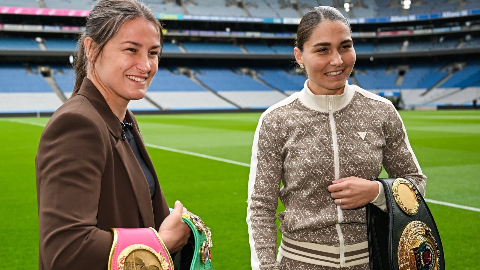 Two female boxers with championship belts on field