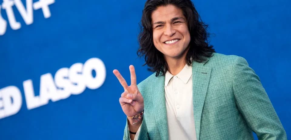 Yoshinori Muto smiling and making peace sign
