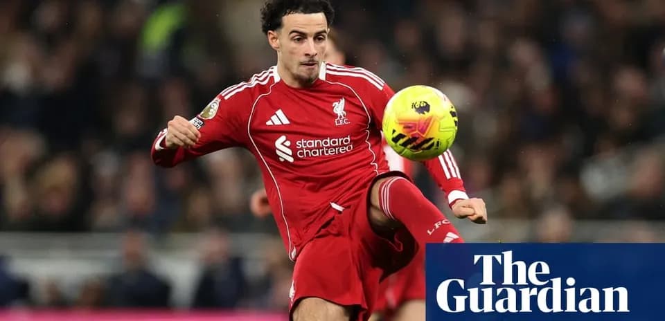 Futbolchi Liverpool formasida to'pni zarb bilan urmoqda