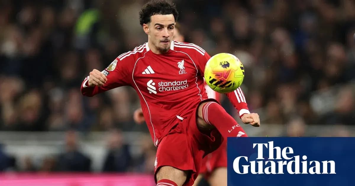 Futbolchi Liverpool formasida to'pni zarb bilan urmoqda
