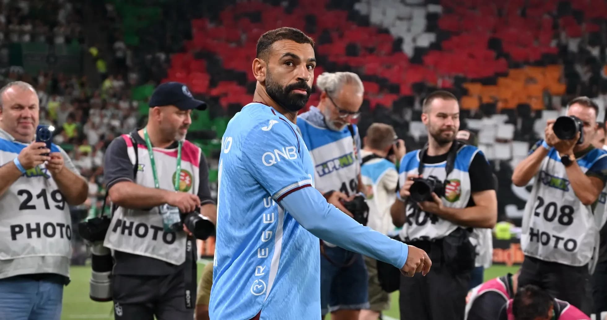 Futbolchi maydonda suratga olish uchun jurnalistlar orasida