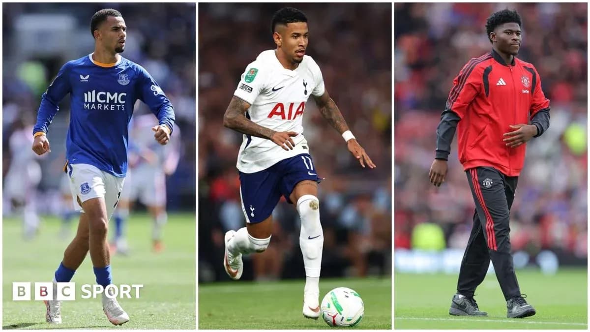 Three football players in club kits on pitch