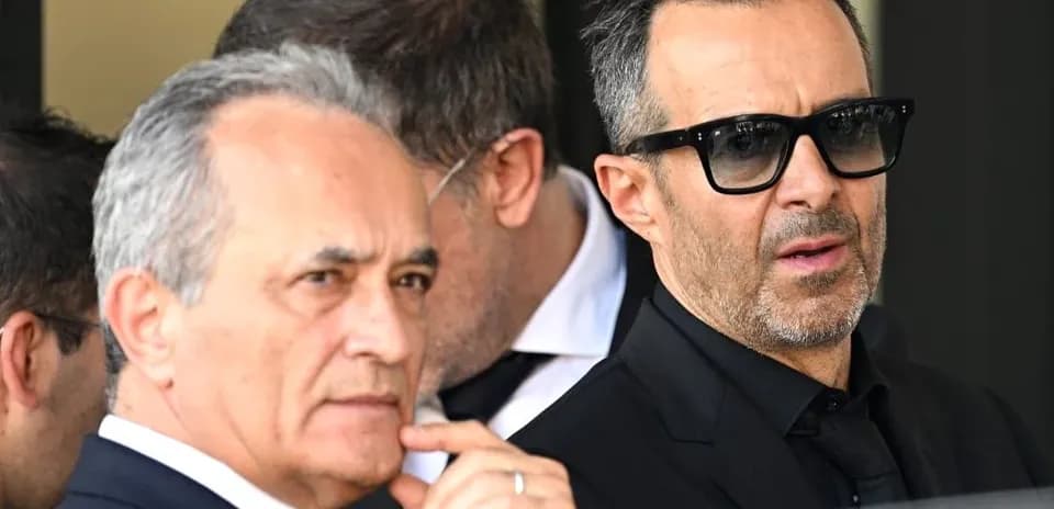 Two men in suits standing outdoors with sunglasses
