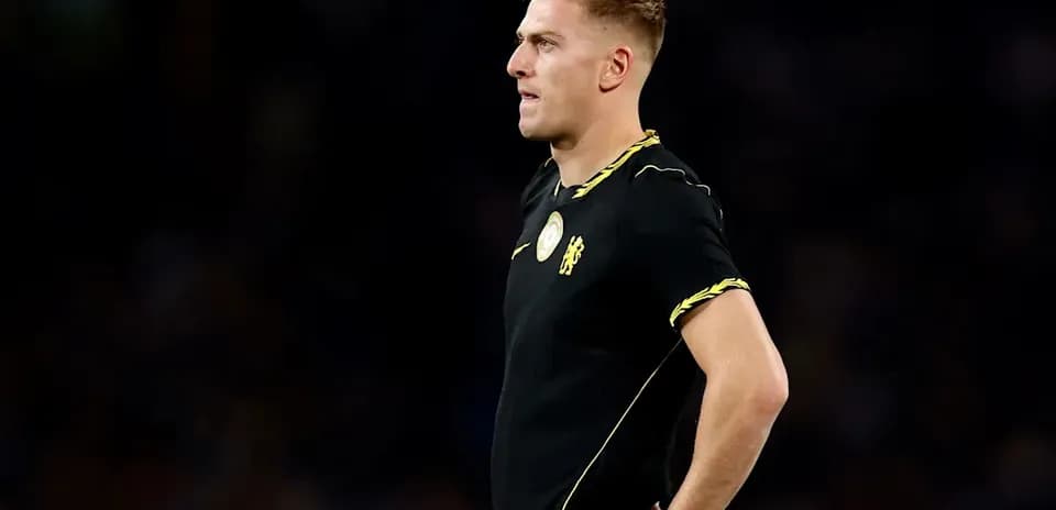 Futbolchi qora formada, maydonni kuzatmoqda