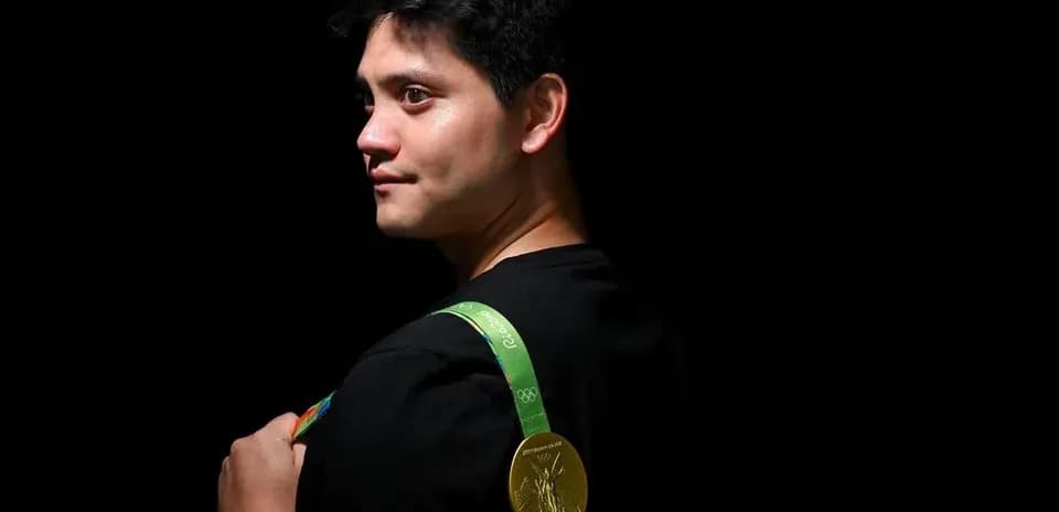 Athlete displaying Olympic gold medal on shoulder