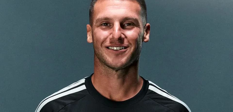 Futbolchi qora formada tabassum qilmoqda