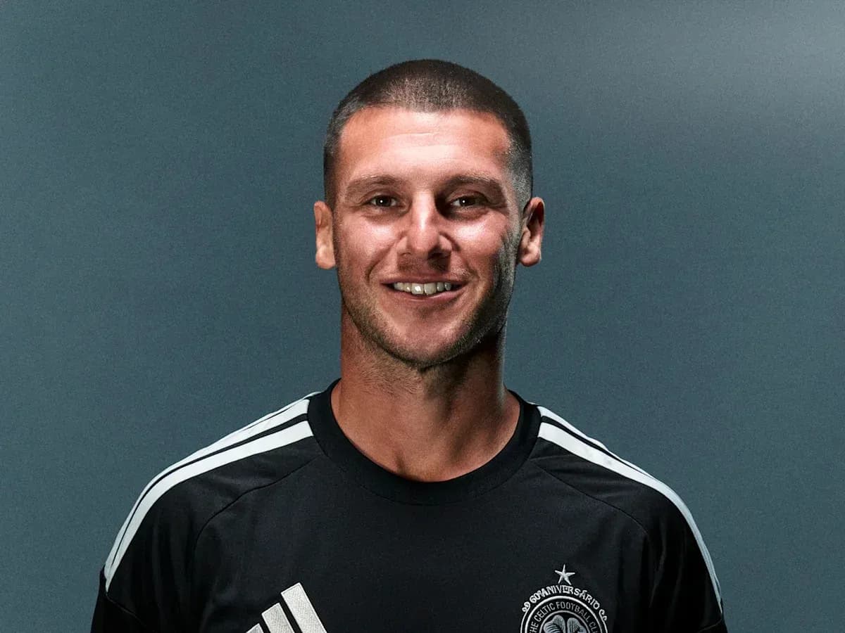 Futbolchi qora formada tabassum qilmoqda