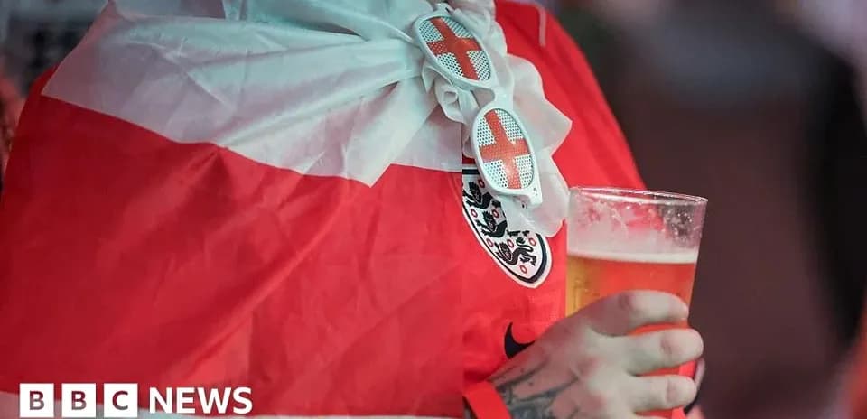 Fan wearing England flag and holding beer