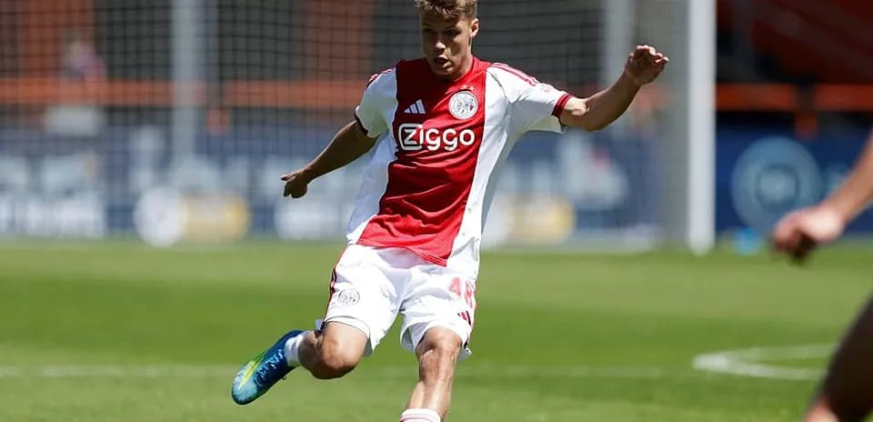 Futbolchi Ajax formasi bilan to'p tepmoqda